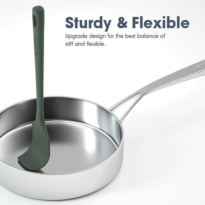 Stainless steel ladle with green handle in a pan on a white background