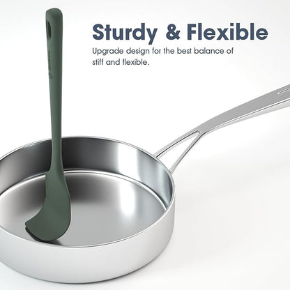 Stainless steel ladle with green handle in a pan on a white background