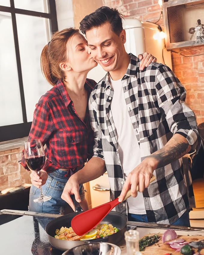 Couple cooking together in a kitchen, woman kissing man on the cheek.